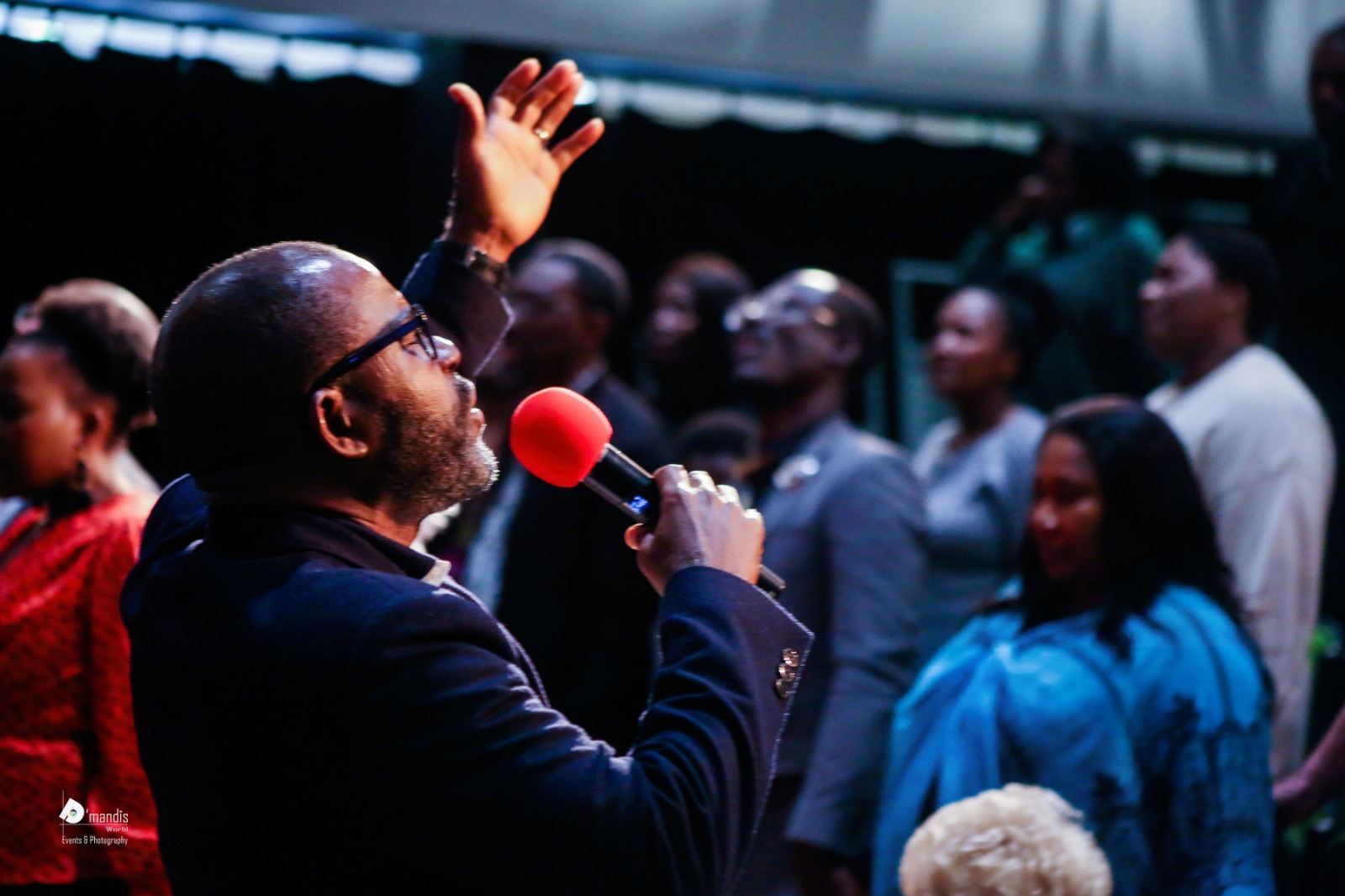 Kingsley Alfred singing into a microphone among the congregation