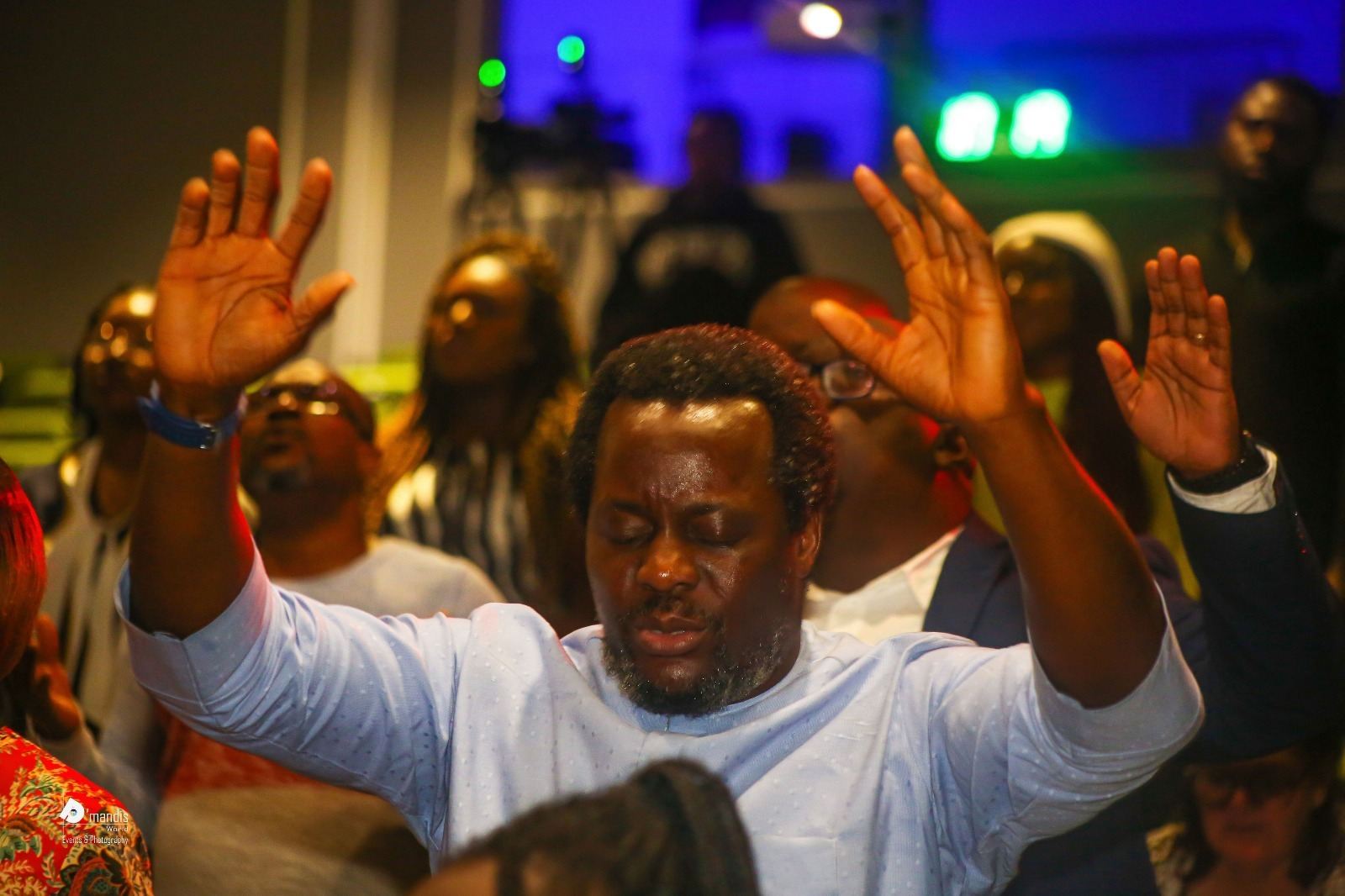 A man worshipping with both hands raised among the congregation