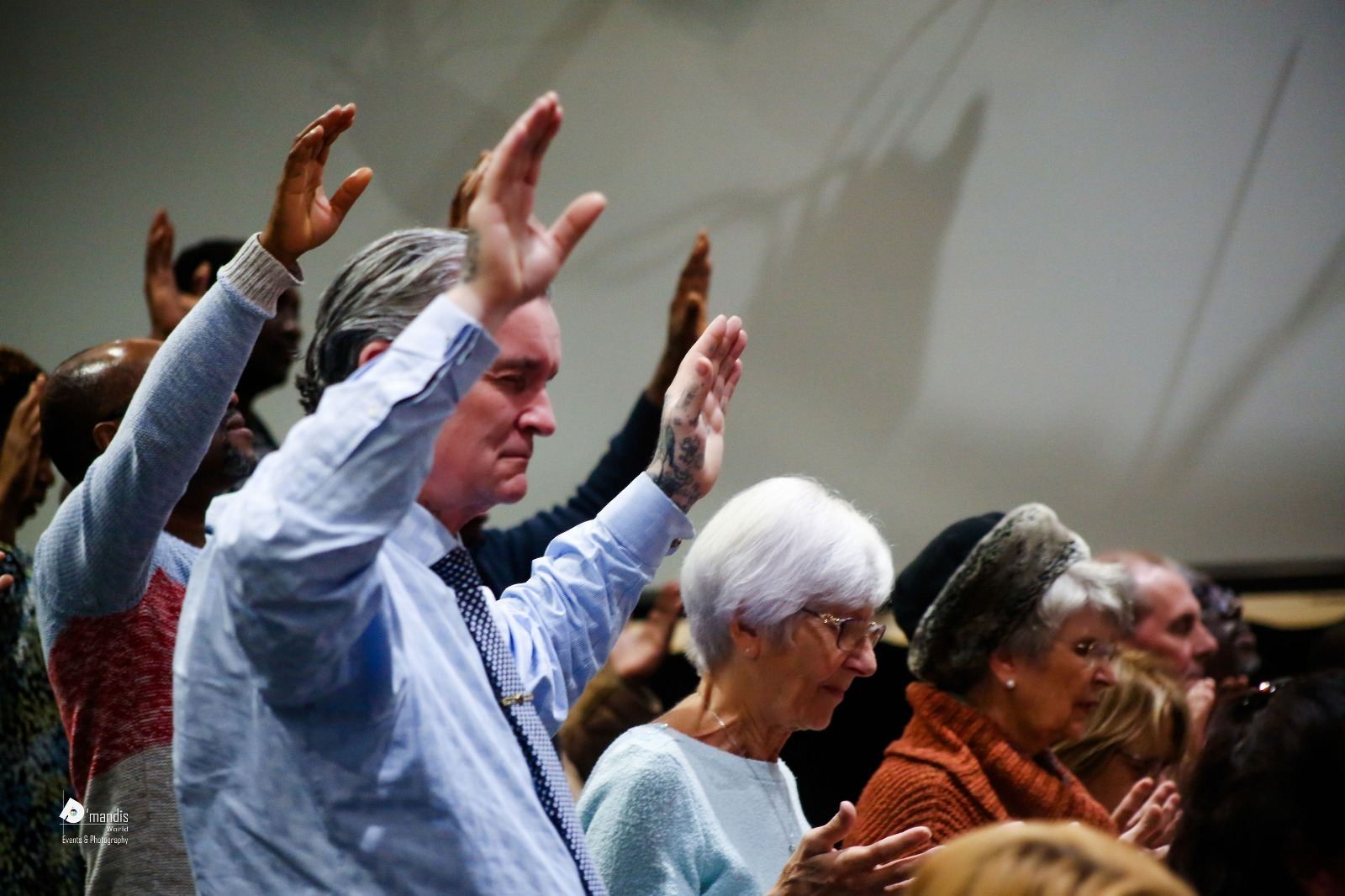 Members of the congregation with arms lifted high in worship